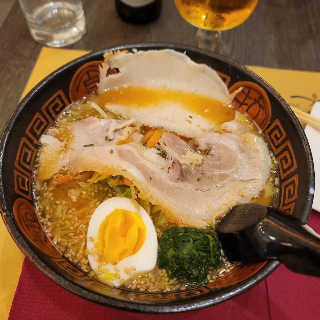 Ramen Hibiki: brodo dorato, chashu di maiale, uovo e sesamo nella ciotola nera della casa